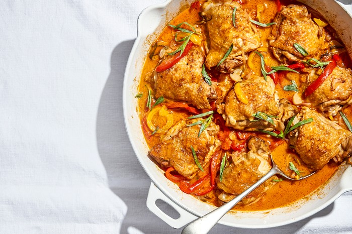 Chicken in red wine vinegar sauce Chicken thighs in a tomato sauce in a white oven dish on a tablecloth