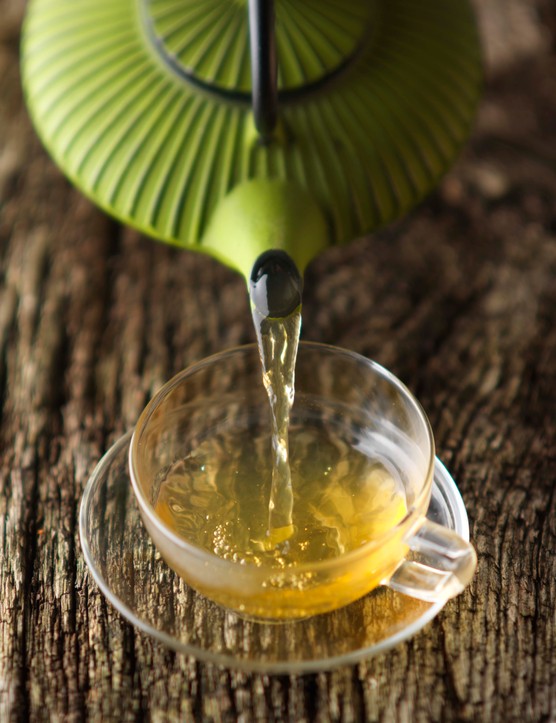 Green Tea Guide A green Japanese teapot pouring green tea into a glass teacup