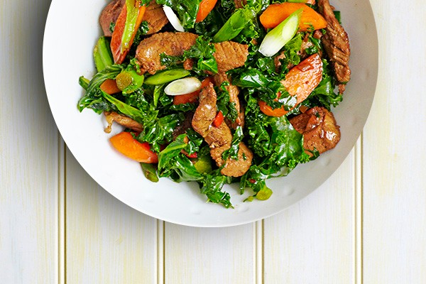 Pork Stir-Fry Recipe with Spring Onions and Kale Pork Stir-Fry Recipe with Spring Onions and Kale served in a round white bowl on a light wooden table