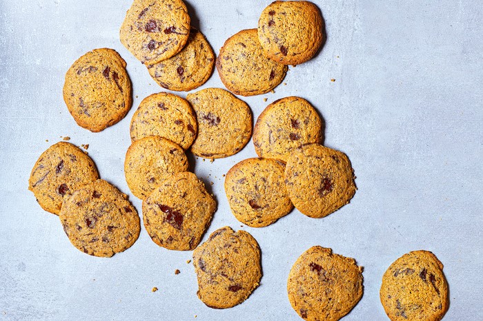 Sourdough rye choc chip cookies A light blue background topped with golden chocolate chip cookies