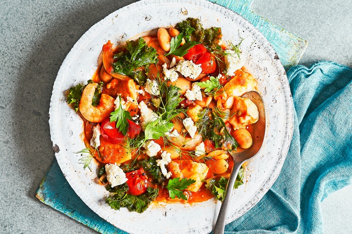 One-pan Fish Stew in a White Bowl on a Blue Wooden Board