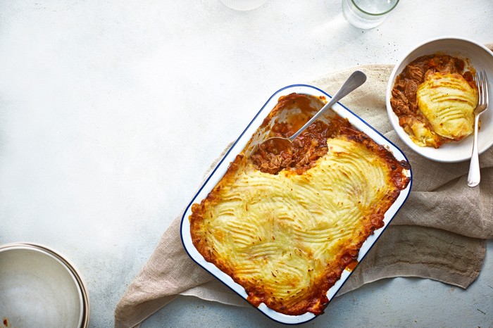 Lamb shank shepherd’s pie A white baking dish filled with a meat pie topped with mashed potato