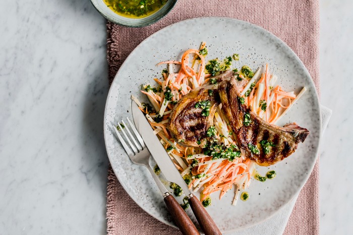 Lamb cutlets A plate topped with two grilled lamb chops and a shredded carrot and celeriac salad with green herbs