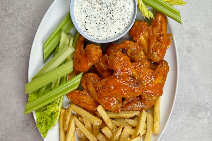 Air-fryer chicken wings Platter of chicken wings, celery sticks and chips next to bowl of dip