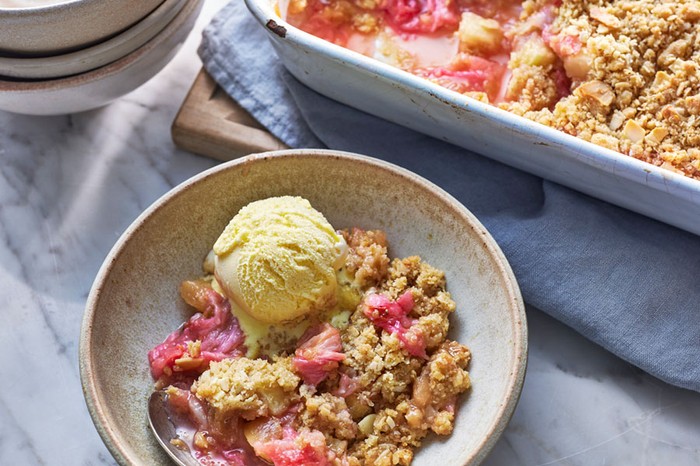 Apple and rhubarb crumble A bowl of crumble and ice cream next to a baking dish of crumble and stack of bowls