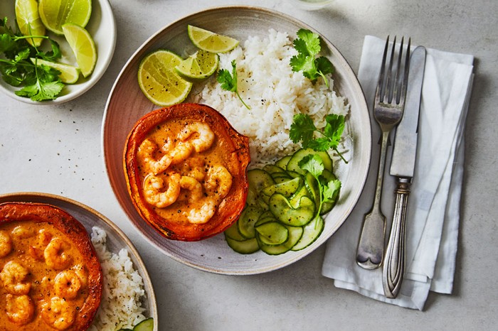 Baked baby pumpkin with red curry prawns Two plates of rice, pickled cucumber and squash filled with prawn curry
