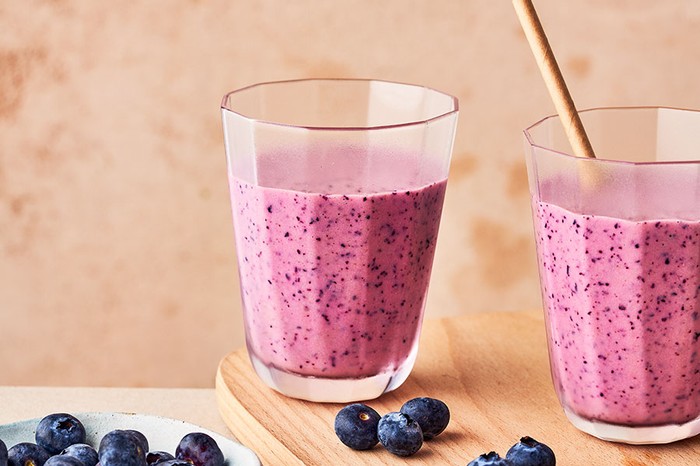 Blueberry smoothie Two glasses full of blueberry smoothie on a wooden serving board