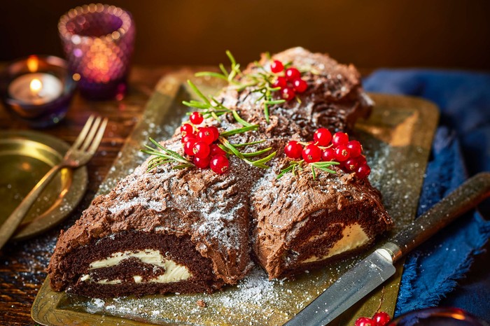 A bûche de noël on a golden serving platter decorated with holly