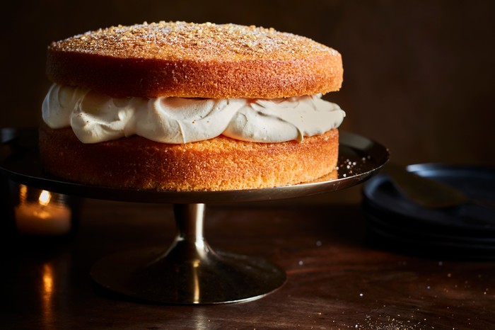 Prosecco cake A sponge cake sandwiched with white cream on a cake stand with a mottled brown background