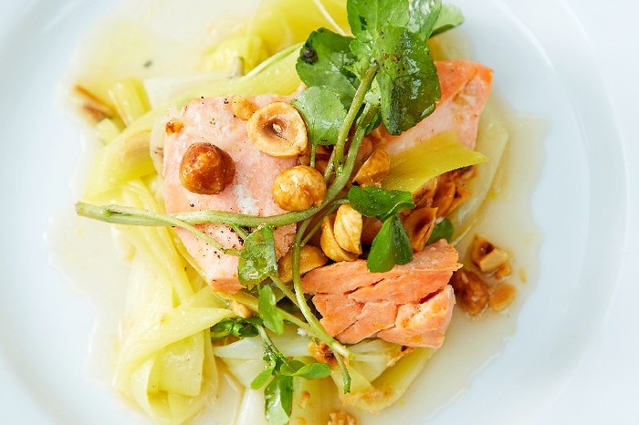 Butter-poached trout, burnt leeks and hazelnuts close up of Butter-poached trout, burnt leeks and hazelnuts on a white plate