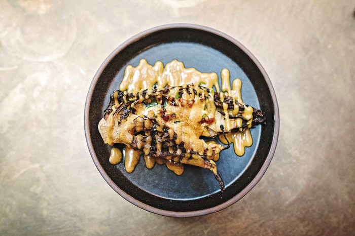 BBQ cabbage A black plate topped with charred cabbage and drizzled with a rich egg yolk sauce