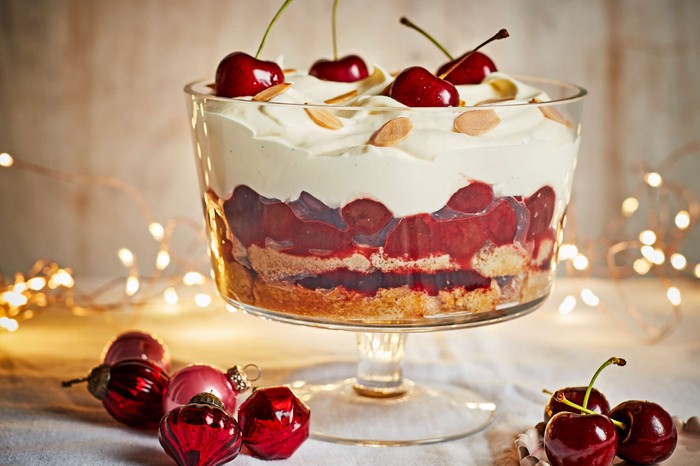 Sour cherry trifle with almonds A cherry trifle in a large glass trifle bowl with fairy lights in the background