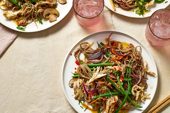 Chicken & soba noodle stir-fry Three plates of colourful stir-fry with drinks on the side