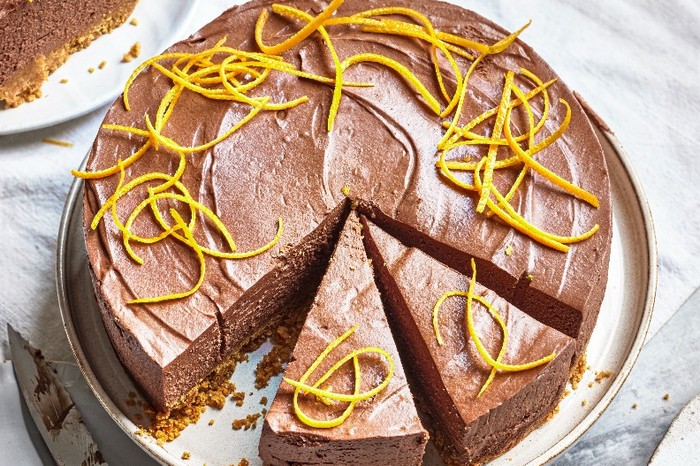 Chocolate orange cheesecake recipe A chocolate cheesecake on a white plate with strips of orange zest on top