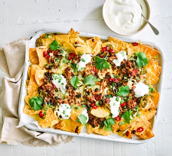 Classic nachos A tray of nachos topped with minced beef, chilli and cheese next to a pot of soured cream