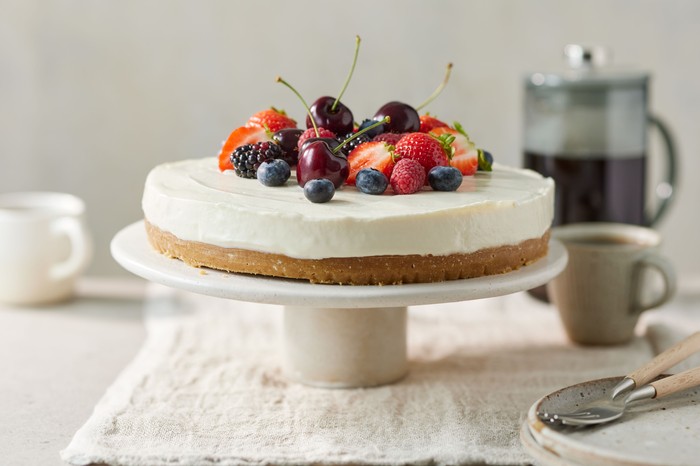 Classic no-bake cheesecake A classic vanilla cheesecake topped with summer berries, presented on a cake stand
