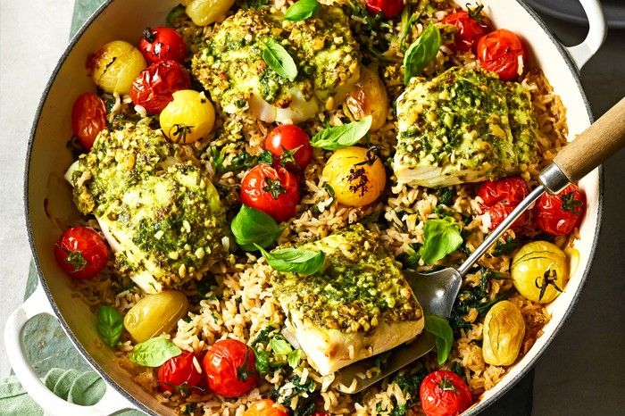 Healthy cod rice one-pot Ceramic cooking pot filled with rice and fillets of cod, with a green napkin