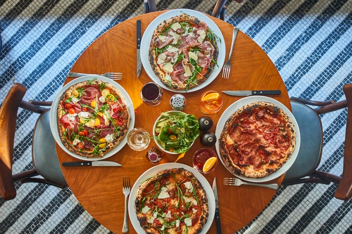 16 Best Italian Restaurants London Selection of pizzas at Cecconi's Pizza Bar, Soho A mahogany table is topped with four pizzas and glasses of Aperol spritz at Soho House's Cecconi's Pizza Bar