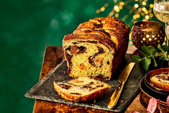 A loaf of cozonac with a marbled centre on a wooden table with a green background