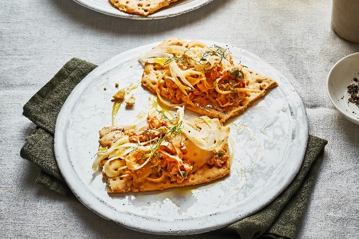Crab toasts Two crisp breads on a white plate topped with crabmeat and fennel