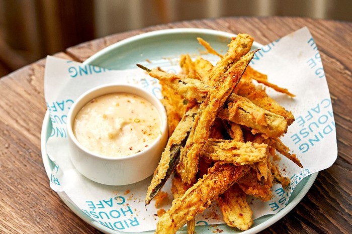 Crispy okra A blue and white pattered plate with deep fried strips of okra and a small pot of creamy dip on a wooden table