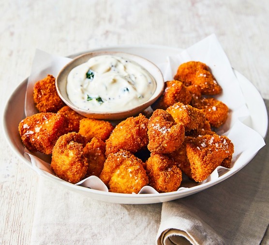 Curried chicken nuggets with curry leaf mayo A white platter of nuggets around a pot of white creamy sauce