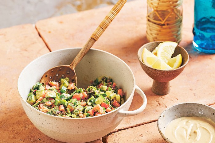 40 vegetarian salad recipes Mixing bowl of Ethiopian salata dakwa salad with a wooden spoon next to a bowl of lemon wedges and dressing