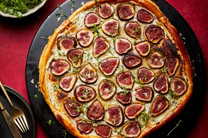 Fig, thyme and ricotta tart A whole fig tart on a black circular serving platter
