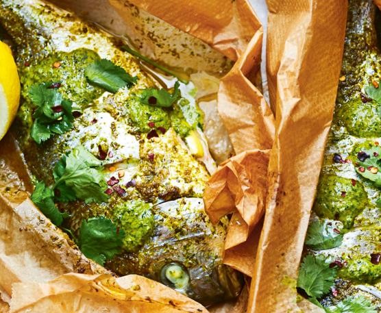 Chermoula fish Whole fish wrapped in paper on a silver baking tray