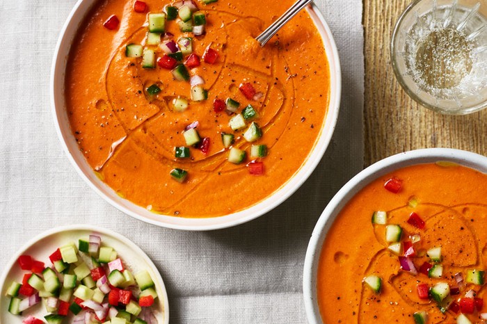 Gazpacho Recipe Two bowls of red gazpacho with a side dish of chopped cucumber and tomato