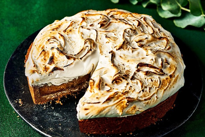A meringue-topped Gingerbread pie on a black plate and green tablecloth