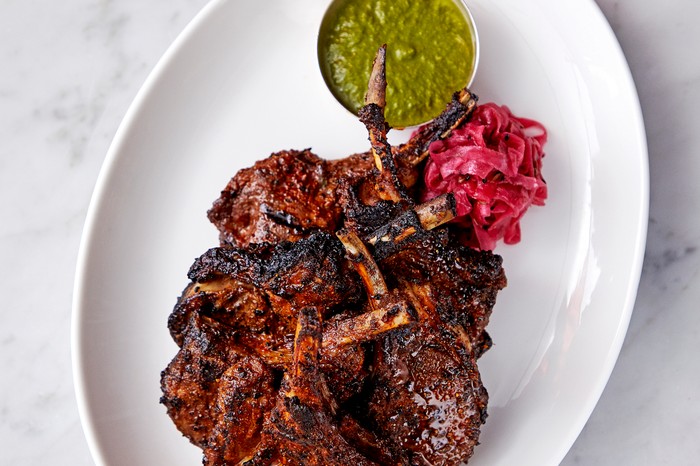 Maa’s Kashmiri lamb chops A white plate topped with griddled lamb chops with a side of green chutney
