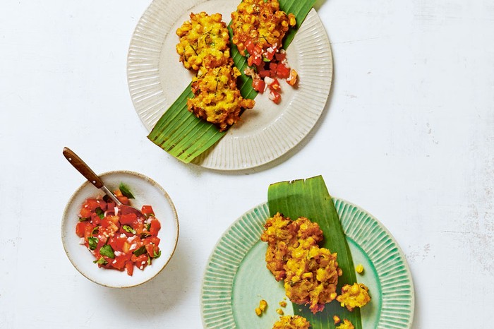 Indonesian-Sweetcorn-fritters-with-chilli-and-tomato-sambal Two plates of sweetcorn fritters next to a bowl of chilli and tomato sambal.