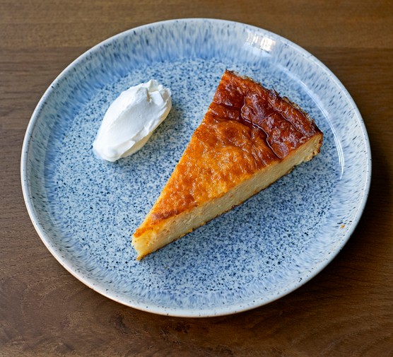 Portokalopita A light blue speckled plate topped with a slice of orange cake, with a quenelle of yogurt on the side