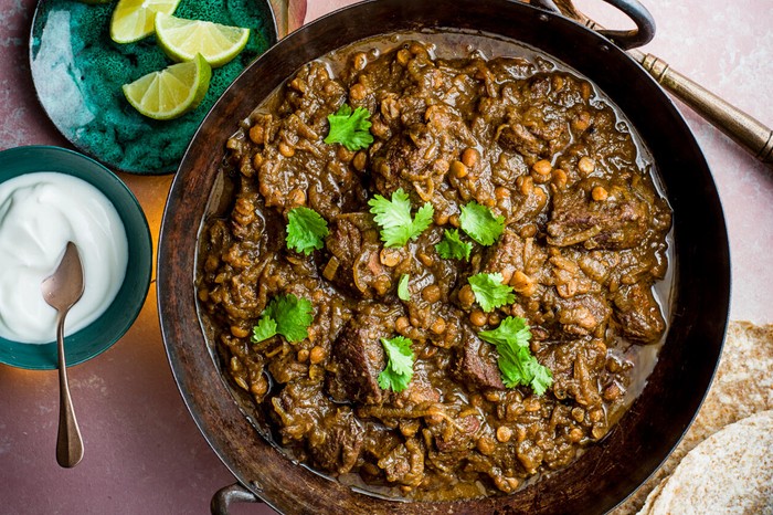 Lamb curry with chana dal A pan of lamb curry with lime wedges on the side