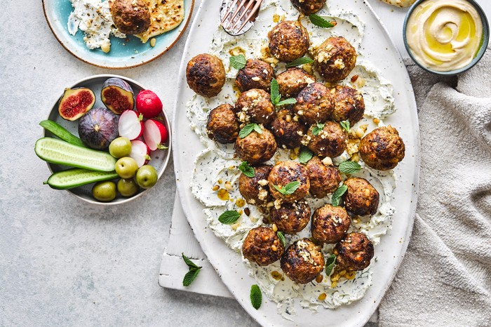 Lamb, date and pine nut meatballs with labneh and dukkah flatbreads A serving platter full of lamb meatballs with little bowls of crudites and dips surrounding it