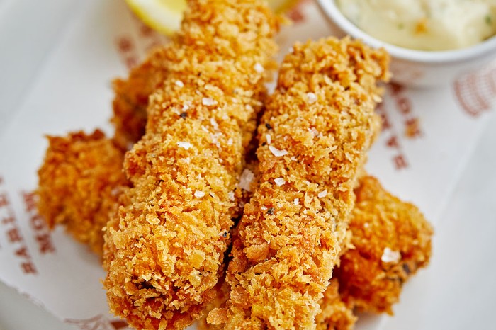 Lamb scrumpets with anchovy mayonnaise Stacked lamb scrumpets next to a ramekin of anchovy mayonnaise and a lemon wedge