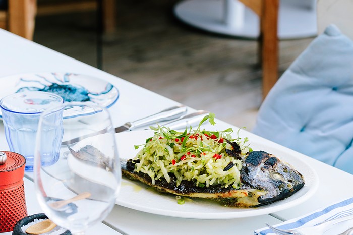 Sea bream with green tomato salsa A table with a white plate topped with cooked fish and a green salsa