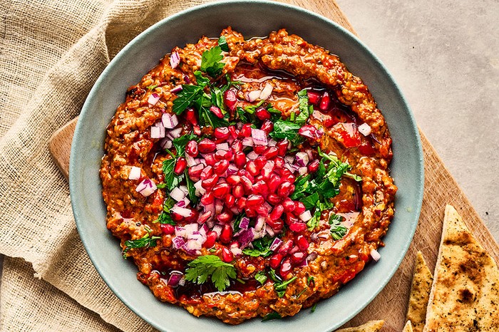 Muhammara A bowl of muhammara topped with red onion, parsley and pomegranate seeds