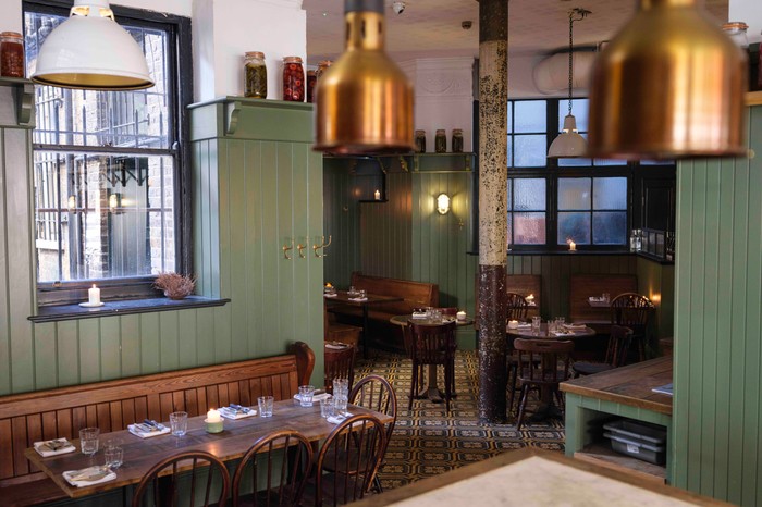 Nest restaurant Hackney The interiors of Nest restaurant Hackney with olive green walls, wooden tables, copper lights and candles