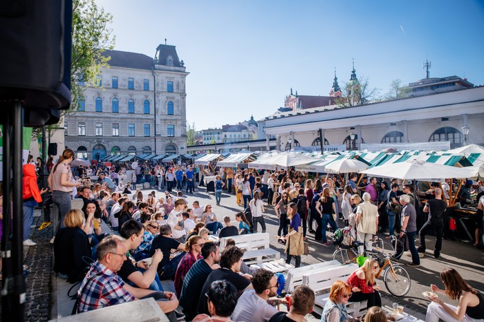 Open Kitchen Market Ljubljana People sat on the pavement by street food stalls at Open Kitchen Market Ljubljana