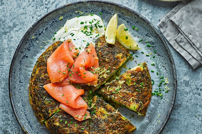 Green Tortilla With Smoked Salmon A blue plate topped with a green tortilla and slices of smoked salmon
