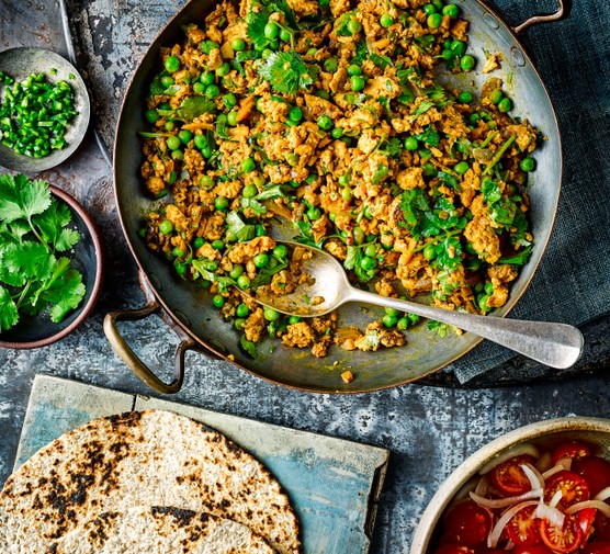 Turkey Keema Curry Recipe Kheema Matar curry with turkey in a large pot with serving spoon, next to a bowl of coriander