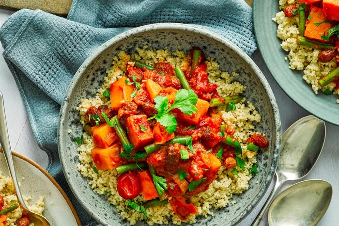 Vegetable Tagine Recipe Squash and sweet potato tagine served in a light blue serving bowl, next to smaller bowls