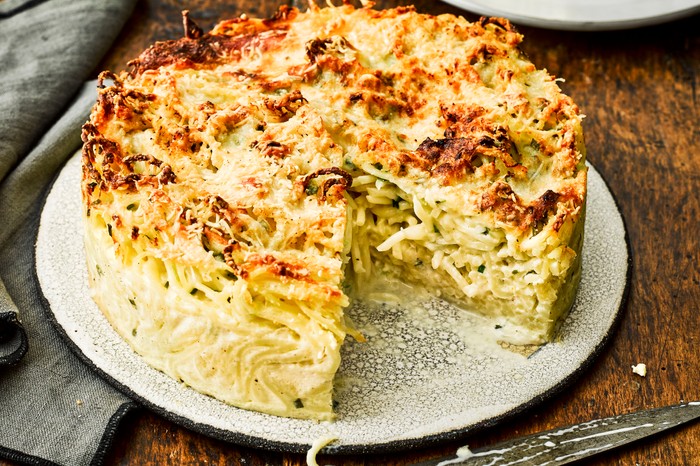Three-Cheese Pie Recipe with Spaghetti A three-cheese pie with a slice taken out to reveal the spaghetti filling