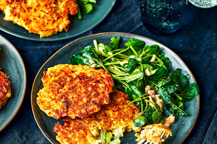 Leek fritters A blue plate topped with two golden fritters, green leaves and a fork