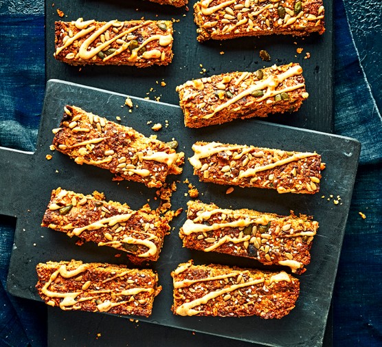 Date flapjacks A slate board topped with slices of golden oat flapjacks, drizzled with peanut butter