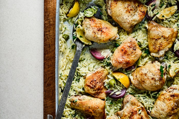 lemon chicken with orzo Traybake with chicken thigh pieces on a bed of orzo and olives