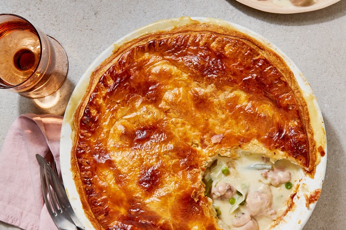 Spring chicken pie A golden-crusted pie with a creamy chicken filling in a pie dish, with a pink napkin and cutlery