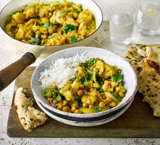 Chickpea and Cauliflower Curry Recipe Pan and bowl of chickpea and cauliflower curry next to some naans